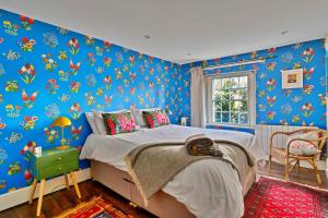 a bedroom with a bed and blue walls with flowers at Finest Retreats - Flittermouse Cottage in Wingfield