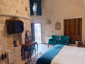 a bedroom with a bed and a tv on a stone wall at Zen Cappadocia House in Göreme
