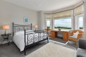 a bedroom with a bed and a desk and windows at 5 Bed in Pwllheli oc-1coedy in Abersoch