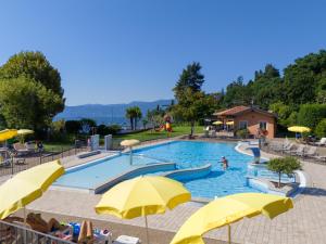 a swimming pool with yellow umbrellas and people in it at Hotel Residence Zust in Verbania