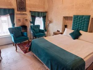 a bedroom with a bed and two chairs and a fireplace at Zen Cappadocia House in Göreme