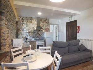 a kitchen and a living room with a table and a couch at Apartamentos Puerta del Castro in Coaña