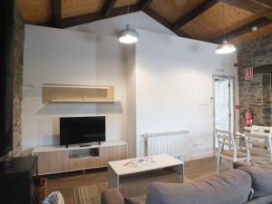 a living room with a couch and a tv at Apartamentos Puerta del Castro in Coaña
