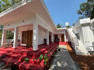 a large white house with a red deck at Tranquil Waves Marari in Mararikulam