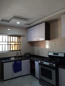 a kitchen with white cabinets and a stove top oven at Pinefield Courts Apartment in Akure