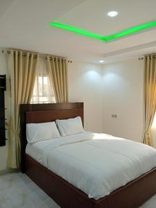 a bedroom with a large bed with a green light at Pinefield Courts Apartment in Akure
