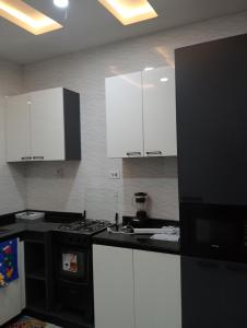 a kitchen with white cabinets and a black stove at Pinefield Courts Apartment in Akure +24 photos