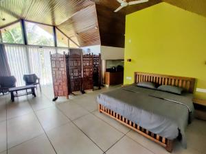 a bedroom with a large bed and a yellow wall at The Vagabond Stays in Vagamon