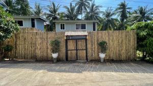 a fence with a wooden gate with two toilets in front of a house at Secret Garden House - 2BR Cozy Home with Garden & Workspace in Ban Tai