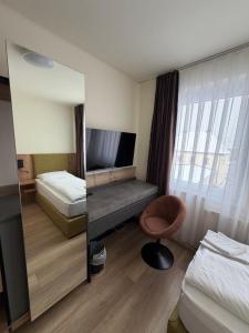 a bedroom with a mirror and a bed and a chair at Turm Inn 24H Self Check In By H&H Hotels in Linz