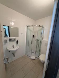 a bathroom with a shower and a toilet and a sink at Turm Inn 24H Self Check In By H&H Hotels in Linz