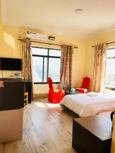 a hotel room with a bed and two red chairs at Gateway Himalaya Resort in Ghanpokhara
