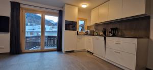 a kitchen with white cabinets and a large window at Alpina Hotel-Apartments in Santa Maria Val Müstair