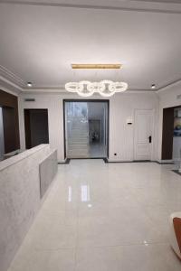 a large white room with a staircase and a chandelier at Huaxia Hotel Bishkek in Bishkek +31 photos
