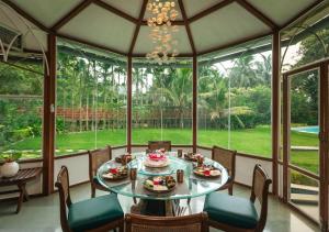 a dining room with a table and chairs and a large window at LohonoStays Villa Lani in Alībāg