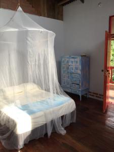 a bedroom with a bed with a canopy and a dresser at Finca San Rafael - Cafe y Cacao in Minca
