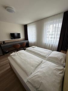 a bedroom with two white beds and a television at Turm Inn 24H Self Check In By H&H Hotels in Linz