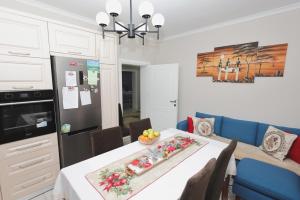 a kitchen and dining room with a white table and blue chairs at Greis Home in Maliq