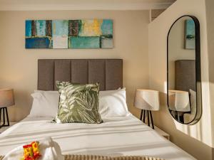 a bedroom with a large white bed and a mirror at Olive Grove Bed & Breakfast in Kraaifontein