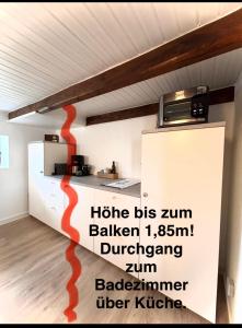 a kitchen with a red painting on the wall at Lüttje Koje - Ferienhaus direkt am Deich und dem Meer dahinter in Norden +6 photos