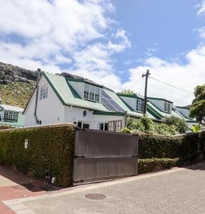 a white house with a fence and a house with solar panels at Majestic Secret in Cape Town