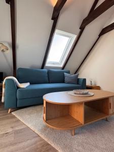 a living room with a blue couch and a table at Lüttje Koje - Ferienhaus direkt am Deich und dem Meer dahinter in Norden