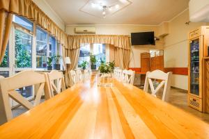 a dining room with a large wooden table and white chairs at Hotel Stadion in Kielce