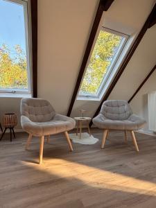 two chairs and a table in a room with two windows at Lüttje Koje - Ferienhaus direkt am Deich und dem Meer dahinter in Norden