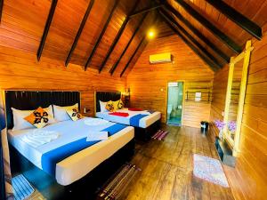 two beds in a room with wooden walls at Sigiriya Carpenter Cottage in Sigiriya