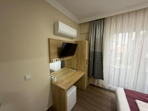 a hotel room with a bed and a desk with a television at Alpaslan Otel Pansiyon in Antalya