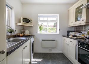a white kitchen with a sink and a window at Quayside Cottage in Waldringfield +14 photos