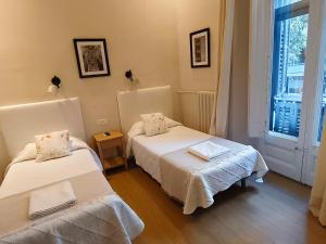 a room with two beds and a window at Casa Consell Bailen, Guest House in Barcelona