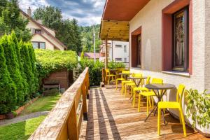 a wooden deck with yellow chairs and tables at Ada in Muszyna