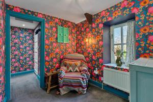 a room with colorful wallpaper and a chair in a room at Finest Retreats - Meadowsweet Cottage in Wingfield