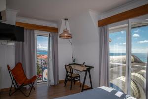 a bedroom with a bed and a desk and a balcony at WOT Ericeira in Ericeira