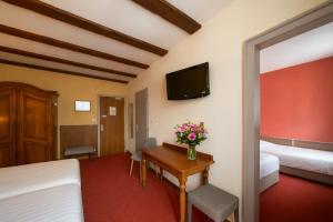 a hotel room with a desk and a tv at Hôtel A la Vignette - COLMAR-NORD in Saint-Hippolyte