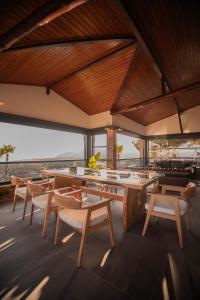 a dining room with tables and chairs and windows at Kaira Kazdaglari in Edremit