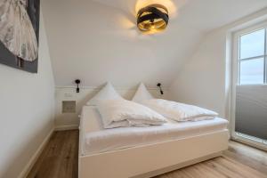 a white bed with pillows on it in a room at Doppelhaushälfte Strandgut 4 in Sylt