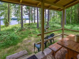 a porch with a wooden table and chairs in the grass at Holiday Home Leppäranta by Interhome in Harjula