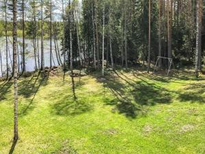 a forest with trees casting shadows on the grass at Holiday Home Inkeri by Interhome in Holiseva