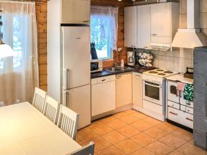 a kitchen with white appliances and a table and a table and chairs at Holiday Home Inkeri by Interhome in Holiseva +19 photos