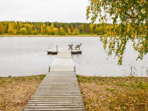 a dock with two benches and a boat on a lake at Holiday Home Vuorimaja by Interhome in Kylänlahti