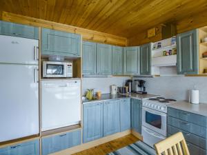 a kitchen with blue cabinets and a white refrigerator at Holiday Home Vuorimaja by Interhome in Kylänlahti