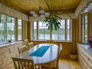 a dining room with a table and chairs and windows at Holiday Home Vuorimaja by Interhome in Kylänlahti +13 photos