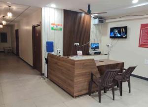 a lobby with a reception desk with chairs and a tv at Sukhnidras Dormitory in Hyderabad