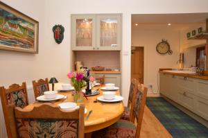 a kitchen with a wooden table with chairs and a dining room at Aldersyde in Tighnabruaich