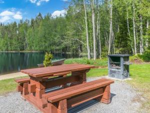 a picnic table and a grill next to a lake at Holiday Home 7734 by Interhome in Kaartilankoski