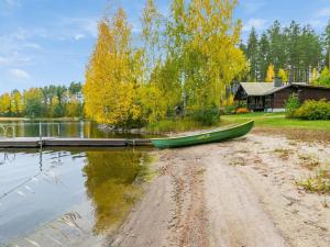 a green canoe sitting on the shore of a lake at Holiday Home Rantalaukka by Interhome in Haapiala
