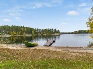 a boat and a bench on the shore of a lake at Holiday Home Rantalaukka by Interhome in Haapiala
