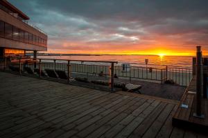 a sunset on a pier with chairs on it at Pirita Beach Apartments & SPA in Tallinn